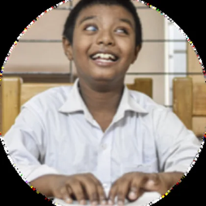 A boy reading a page of braille with his fingers, smiling.