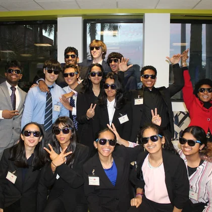 A cohort of students in business dress celebrating together.